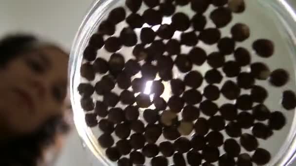 Ung kvinna scattering hasselnötter i en glasskål — Stockvideo