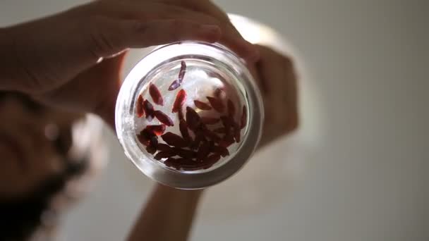 Молодая женщина, разбрасывающая ягоды годжи в стакане — стоковое видео