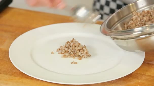 Boiled buckwheat on a white plate — Stock Video