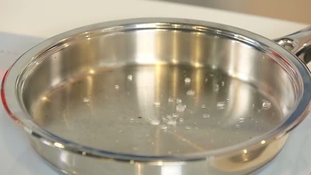 Капает воду на раскаленную сковородку — стоковое видео