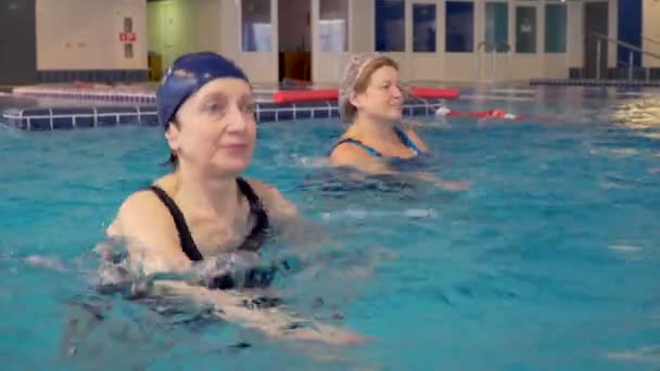 Skupina vedoucích žen dělá cvičení aqua aerobic v bazénu — Stock video