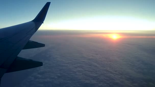 Puesta de sol sobre las nubes a través de la ventana de un avión — Vídeo de stock