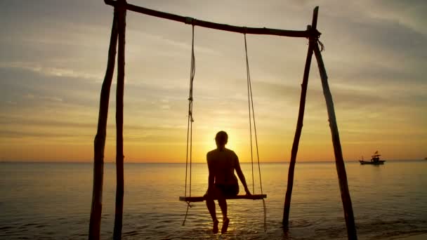 Mädchen auf einer Schaukel am Strand bei Sonnenuntergang — Stockvideo