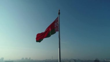 Beyaz Rusya bayrağı mavi gökyüzü ve güneşli bir sabahta Minsk şehri üzerinde dalgalanıyor.