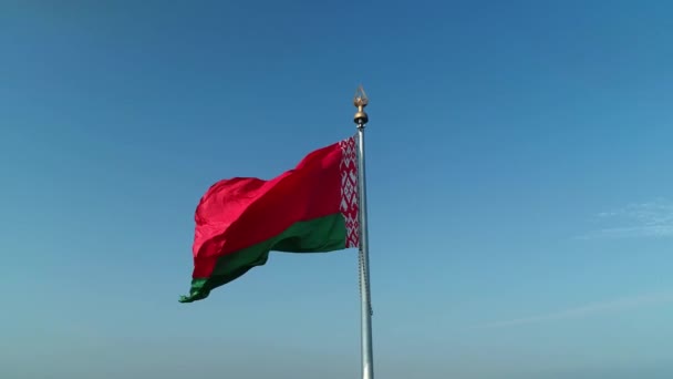 Běloruská vlajka vlnící se nad modrou oblohou za slunečného rána — Stock video