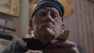 Tekerlekli sandalyedeki yaşlı erkek usta atölyesinde mobilyaları restore ediyor.