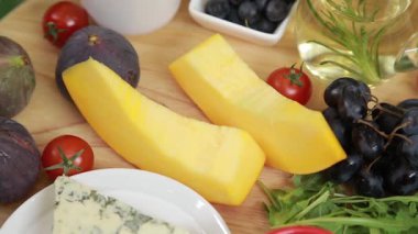 Raw pumpkin with different fresh fruits, vegetables, greens and cheese as ingredients for warm salad with figs and blue cheese