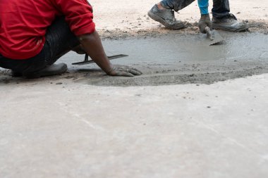 İşçiler beton zemini düzleştiriyor..