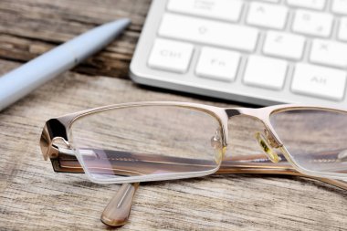 Klavye bilgisayar ve kalem eski ahşap masa üzerinde gözlük