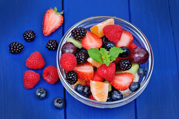 Свежий фруктовый салат в миске на деревянном столе
