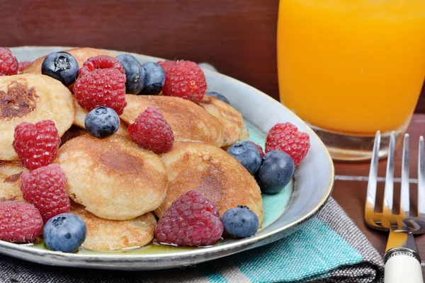Mini-Pfannkuchen mit Beeren und Orangensaft auf dem Tisch — Stockfoto
