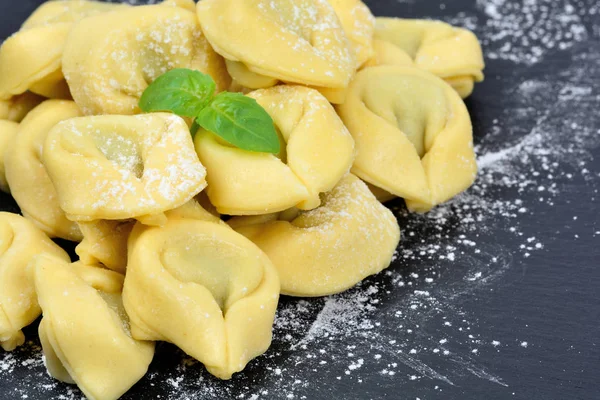 Italské tradiční tortellini těstoviny a bílá mouka na břidlici — Stock fotografie