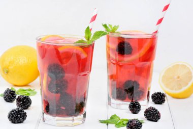 Beyaz bir arka plan üzerinde bir bardak böğürtlen limonata