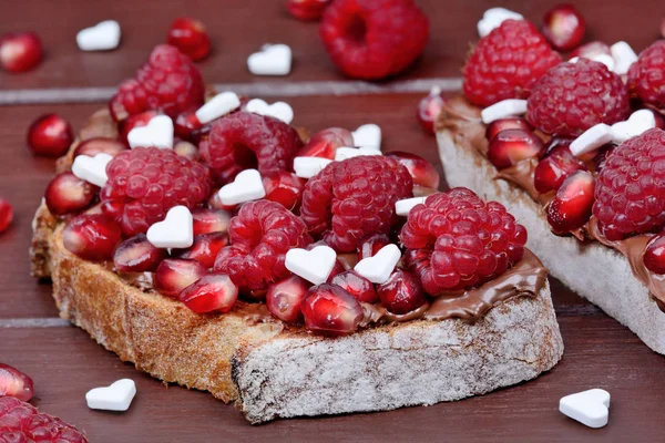 Dos rebanadas de pan con chocolate y frambuesa en la mesa — Foto de stock gratis