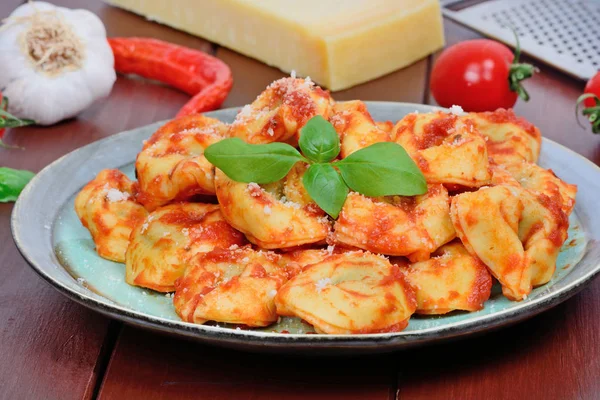 Tortellini med tomatsås i en tallrik på träbord — Stockfoto