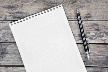 Eski ahşap bir masaya yakın çekim kalemli boş bir defter