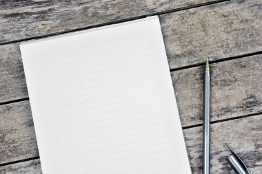 Eski ahşap bir masanın üzerinde boş bir not defteri.