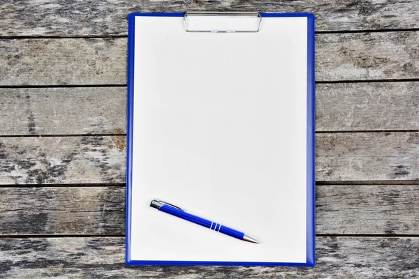 Empty clipboard with pen on a wood table