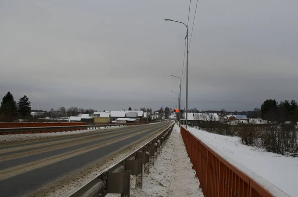 Otoyol M8 Arkhangelsk, kışın Moskova. Nehrin karşısındaki otomobil köprüsü. Yol boyunca küçük bir köy. Rusça yazıt: 