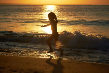 gün batımında sahilde oynarken çocuk
