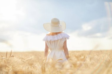 gündüz sırasında buğday alanında şapkalı beyaz kadın