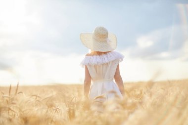 gündüz sırasında buğday alanında şapkalı beyaz kadın