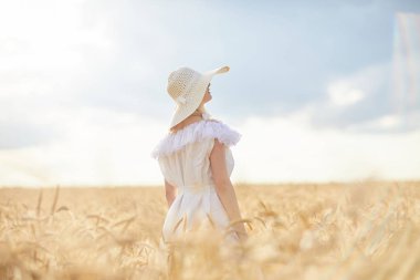 gündüz sırasında buğday alanında şapkalı beyaz kadın