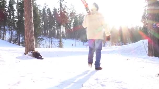 Homme va avec des skis à la station de ski contre le soleil brillant — Video