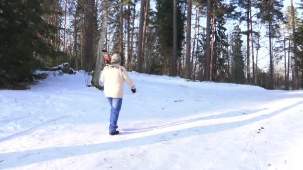 Пожилой лыжник в синих джинсах уходит вглубь соснового леса — стоковое видео