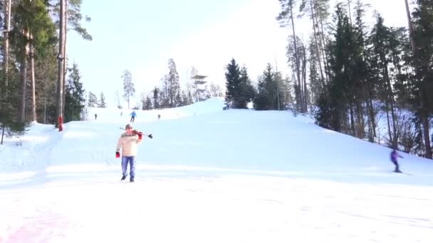 Senior man in red gloves walks downhill against ski resort — Stock Video