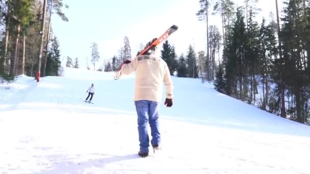 穿蓝色牛仔裤和毛衣的男人上山滑雪坡 — 图库视频影像