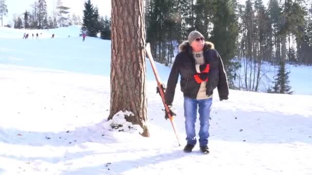 Congelado homem no preto inverno jaqueta fica por árvore e sorri — Vídeo de Stock