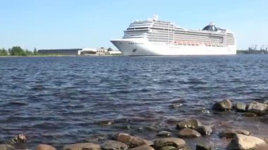 Büyük MSC Poesia gemisi mavi gökyüzünün altında Daugava nehrinde yelken açıyor
