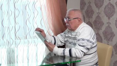 Gözlüklü son sınıf öğrencisi oturup gümüş sekmede haber okuyor.