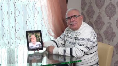 Gözlüklü kibar yaşlı adam kendi portresi olan bir tabela tutuyor.