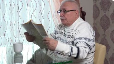 Adam şeffaf masada oturur haritadan bakar ve çay içer.