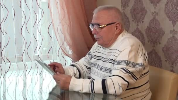 Old man in sweatshirt holds tablet shows self retrait. — Vídeo de stock