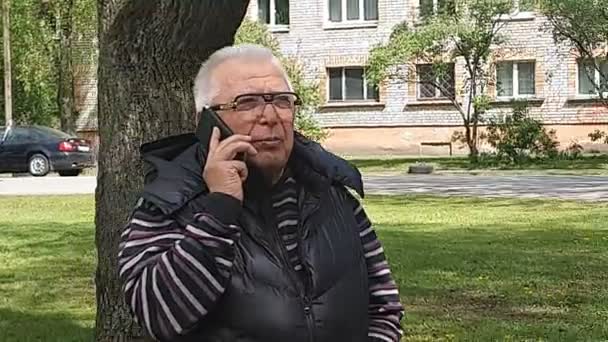 Movimento em torno de homem sênior usando telefone celular no jardim da cidade — Vídeo de Stock