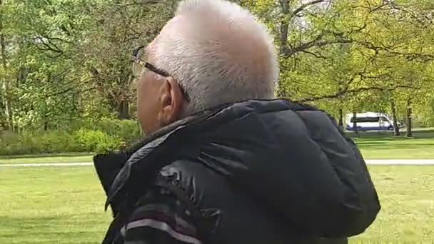 Senior man rust praten op mobiele telefoon in prachtig park — Stockvideo