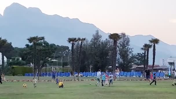 Adults teach local children to play football on grass field — Stock Video