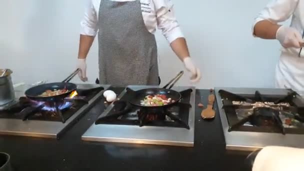 Los cocineros tranquilos freír deliciosas comidas en las sartenes usando llama. — Vídeo de stock