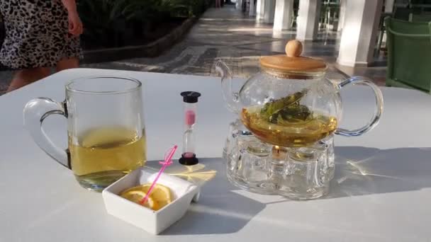 Green tea with orange and hourglass stand on white table — Stock Video