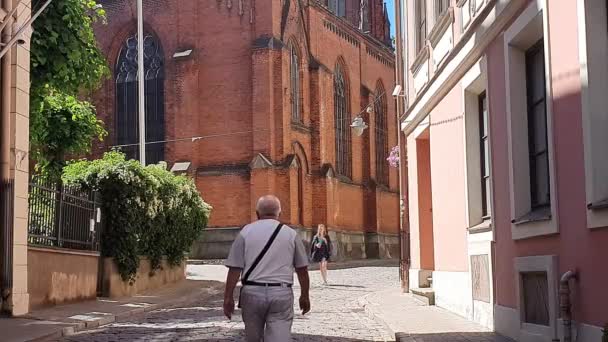 Homme marche vers l'église ancienne fille à la jupe noire eau potable — Video