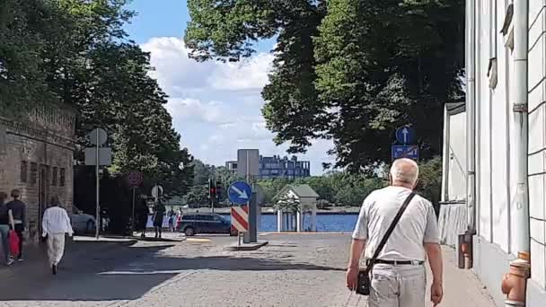 El hombre camina por la calle contra la carretera y el hermoso río — Vídeos de Stock