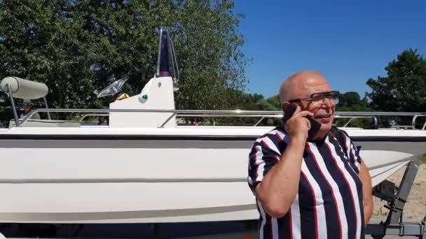 Senior man has conversation on cellphone at cater on piers. — Vídeos de Stock