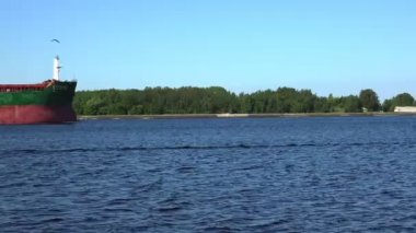 kırmızı ve yeşil kargo gemisi geniş nehir boyunca yavaşça yelken