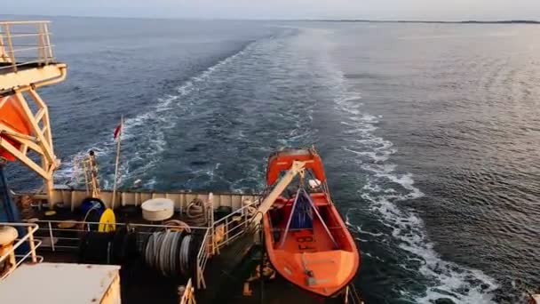 Грузовое судно с оранжевой спасательной лодкой на кормовых парусах на реке — стоковое видео