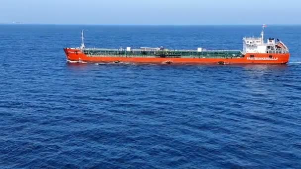 Długi czerwony zbiornikowiec z kolorowymi rurami żaglami na niekończącym się morzu — Wideo stockowe