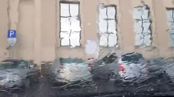 Carros embaçados no estacionamento por construção vista através da chuva — Vídeo de Stock