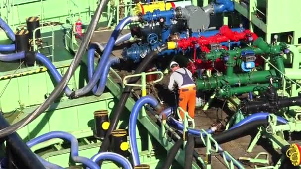 Человек в комбинезоне работает с зеленым краном на нефтяном танкере — стоковое видео